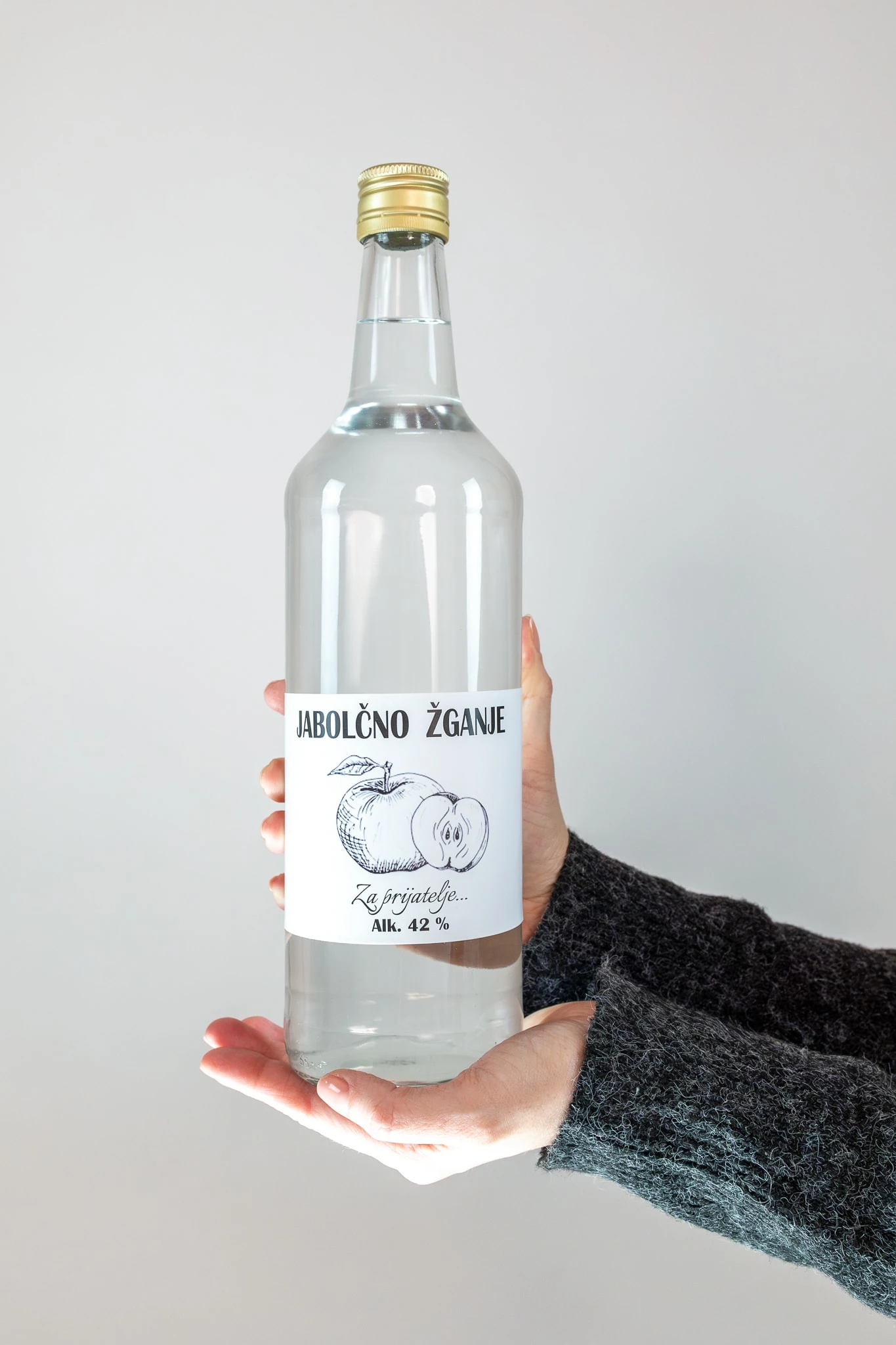 Roki držita steklenico jabolčnega žganja